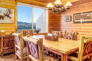 Un interior de madera con una mesa de comedor, bancos y una araña.