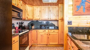 A wooden cabin-style kitchen with granite countertops, wooden cabinets, a microwave, toaster, and a sink. - Unique 7th Floor Penthouse. Views. Hot Tub Balcony (Frisco)