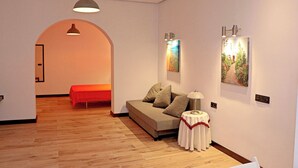 A modern living room with a sofa, a small round table, and two wall-mounted lamps.