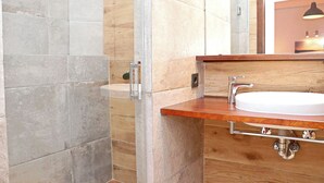 A bathroom with a wooden vanity, a white sink, and a shower area with a glass door.