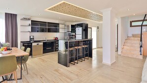 A modern kitchen with a central island, built-in appliances, and a dining area with a table and chairs.
