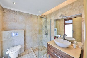 Ein modernes Badezimmer mit einer Glaskabine zur Dusche, einem großzügigen Waschbecken und einem Spiegel über dem Waschtisch.
