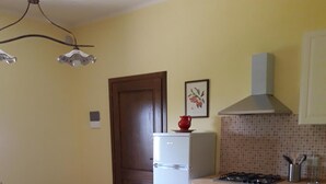 A kitchen with a dining table, chairs, a refrigerator, a stove, and a tiled backsplash.