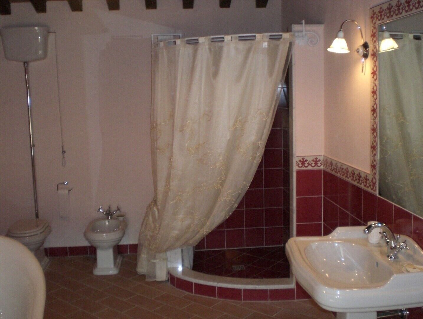 A bathroom with a toilet, bidet, shower, and sink.