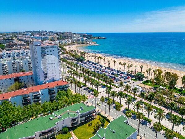 A coastal cityscape with a beachfront, palm-lined promenade, and high-rise buildings.