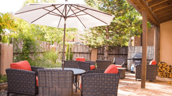 Une terrasse extérieure avec des meubles en osier et un grand parasol.