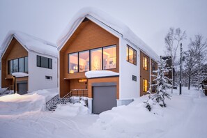 A modern two-story house with large windows, a wooden facade, and a snow-covered roof. - Koa Niseko (Niseko)