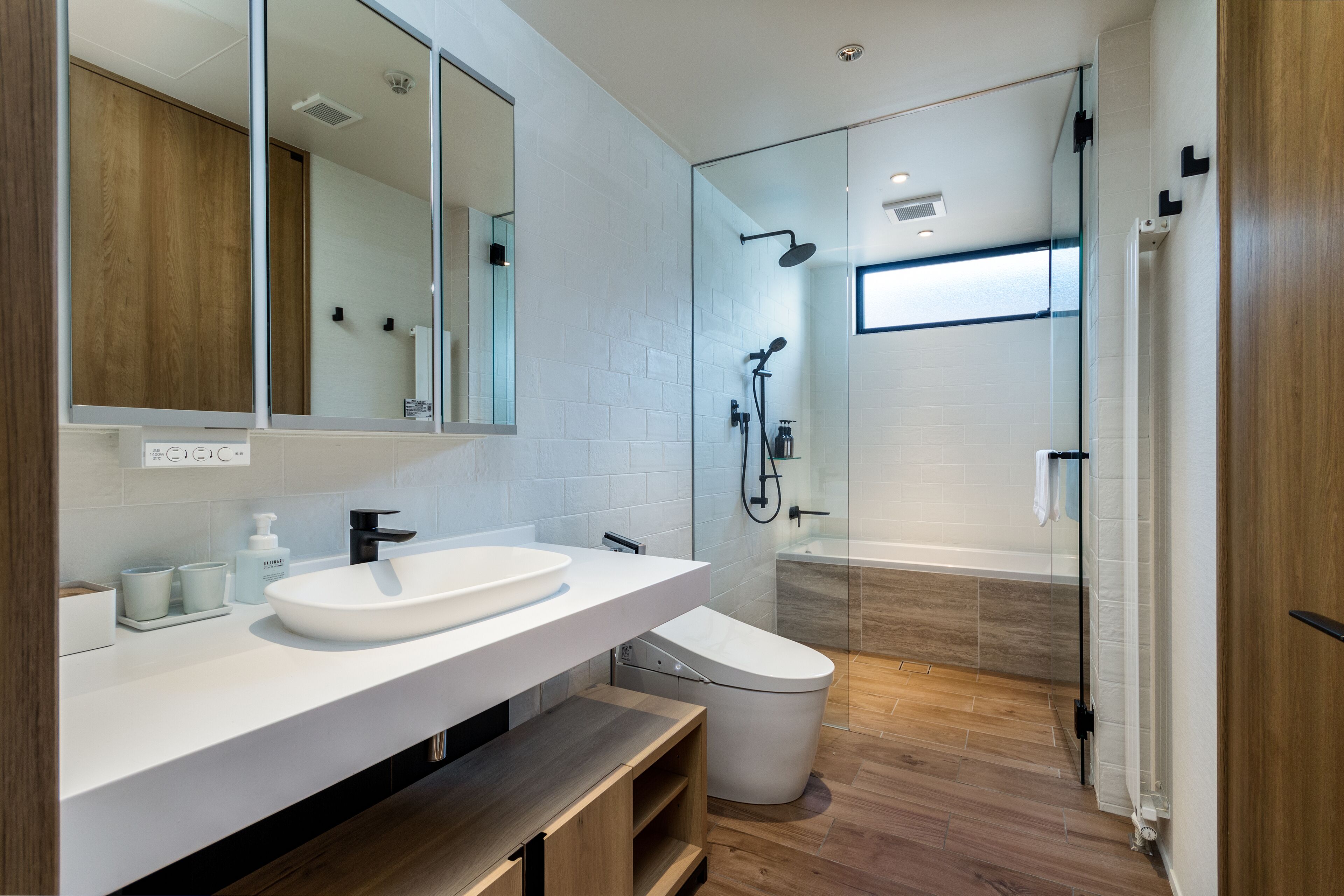 A modern bathroom with a white sink, a toilet, and a glass-enclosed shower.