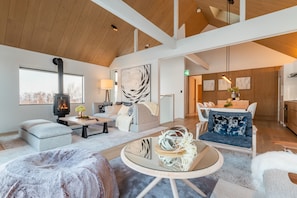 A spacious living room with a fireplace, a sofa, a coffee table, and a dining area with chairs.