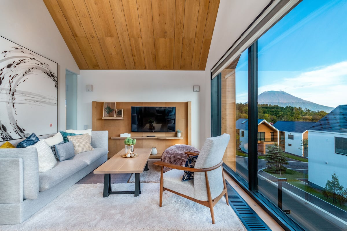 A modern living room with a large window, a sofa, a coffee table, and a chair.