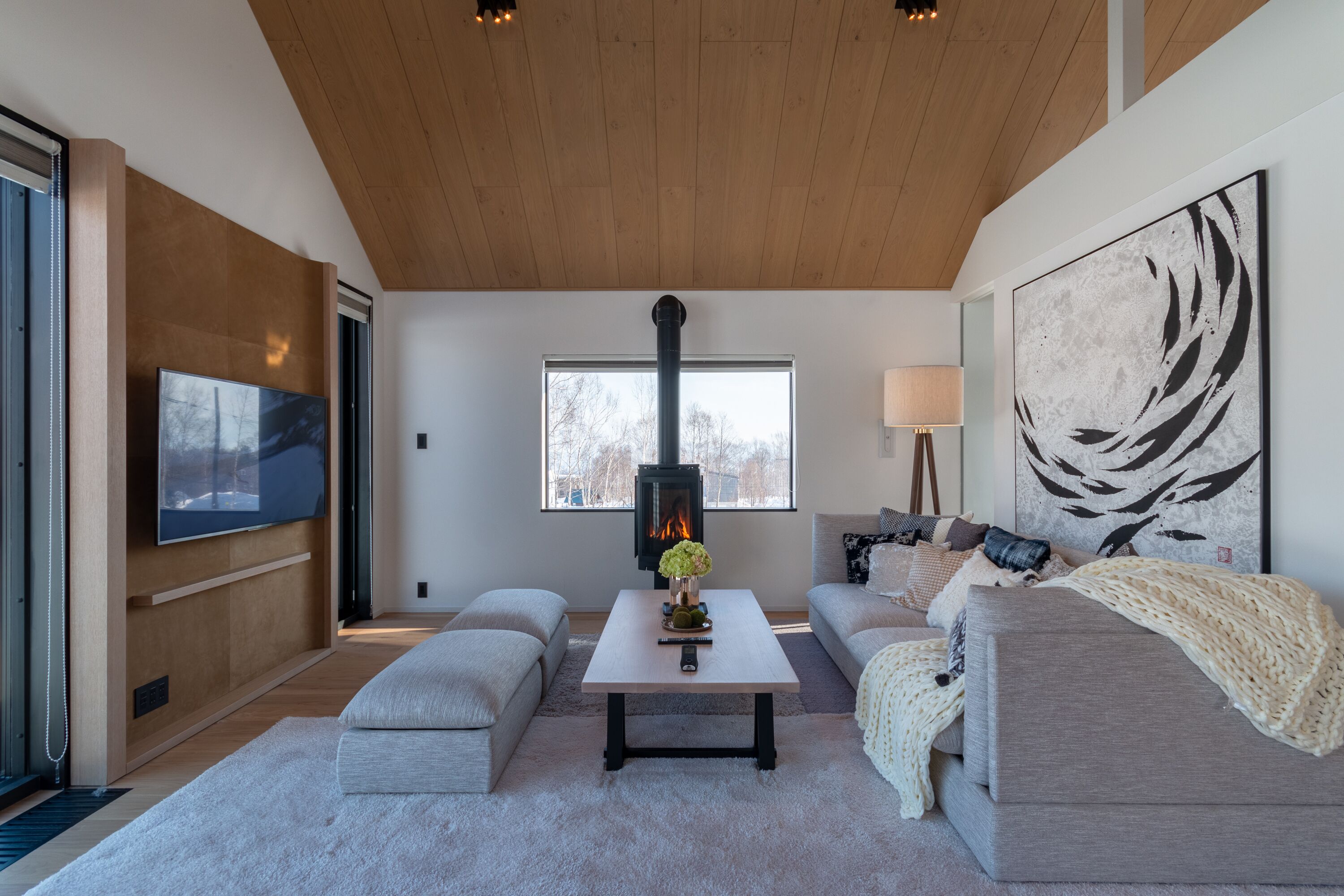 A modern living room with a fireplace, sofas, a coffee table, and a large abstract painting.