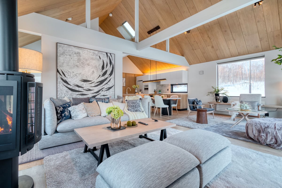 A modern living room with a fireplace, grey sofas, a coffee table, and a large abstract painting.