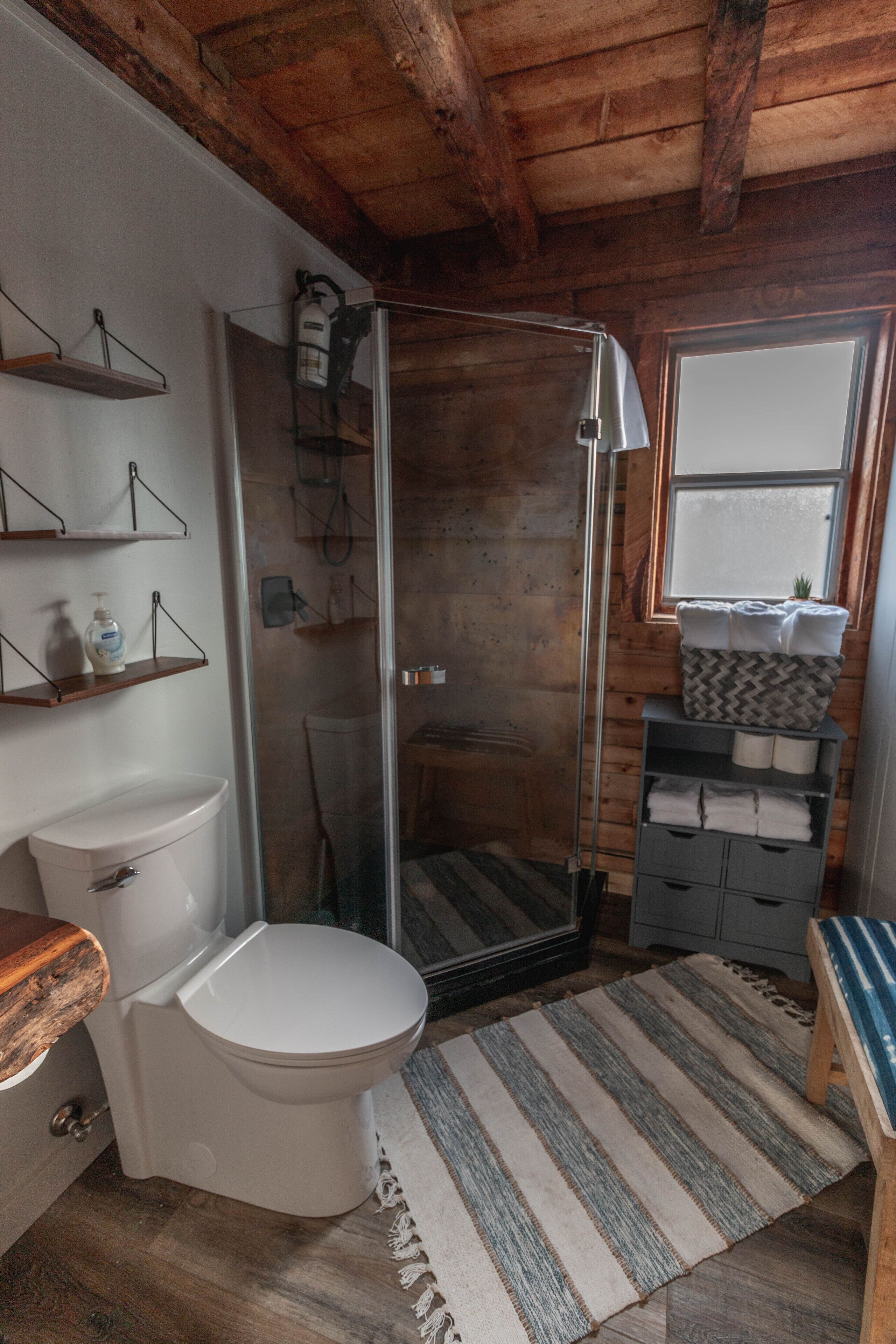 Une salle de bain comprenant des toilettes, un espace douche, un lavabo et une fenêtre.