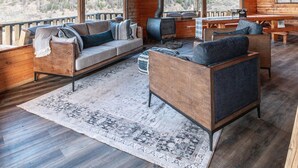 A log cabin interior with a large sofa, wooden dining table, and a fireplace. - Disconnect From Technology And Reconnect With Nature - Sleeps 6 (Lake City)