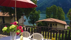A terrace with a table, chairs, a vase with flowers, a bottle, and a hula hoop. - Directly on the lake with terrace and two bedrooms (Idro)