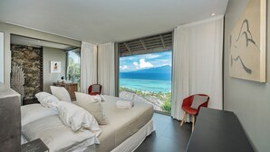 A modern hotel room with a bed, a desk, and a view of the ocean. - Beautiful architect villa overlooking the lagoon and the island of Tahiti (Te'avaro)