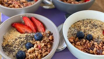 Three bowls of oatmeal with strawberries and blueberries on a wooden table.