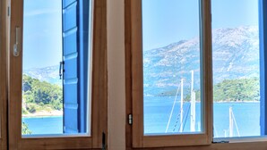 A room with two windows overlooking a body of water and a mountainous landscape. - Eco Aparthotel The Dreamers' Club - Garden for 4 (Lumbarda)
