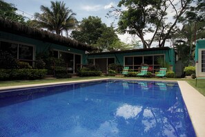Una piscina al aire libre, sillones reclinables de piscina