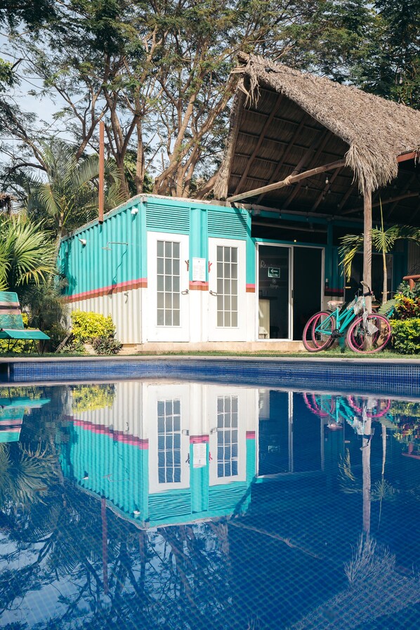 Un bâtiment avec un toit de chaume, un vélo et une piscine.