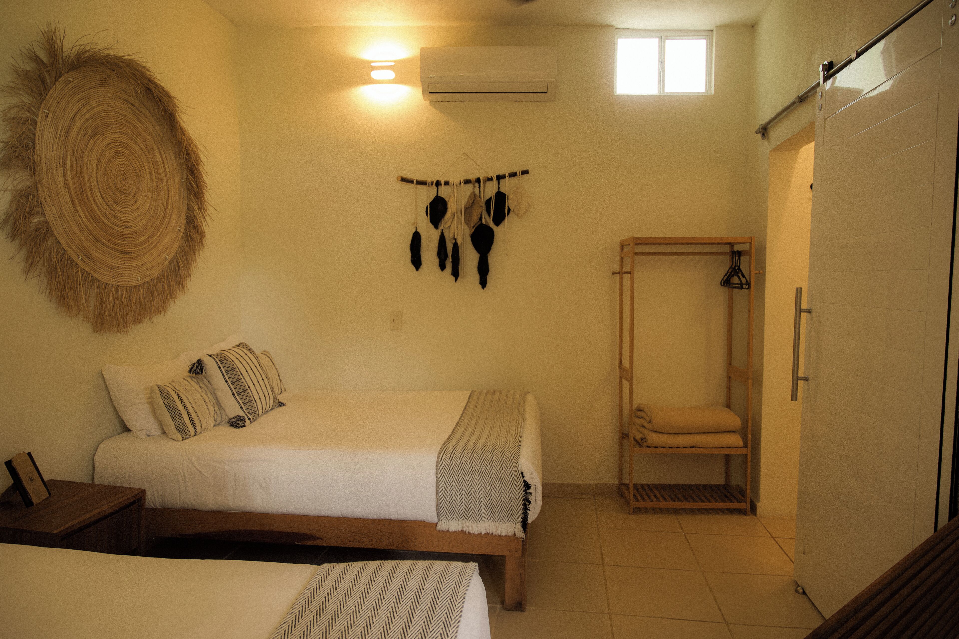 A bedroom with two beds, a hanging light fixture, and a wardrobe.