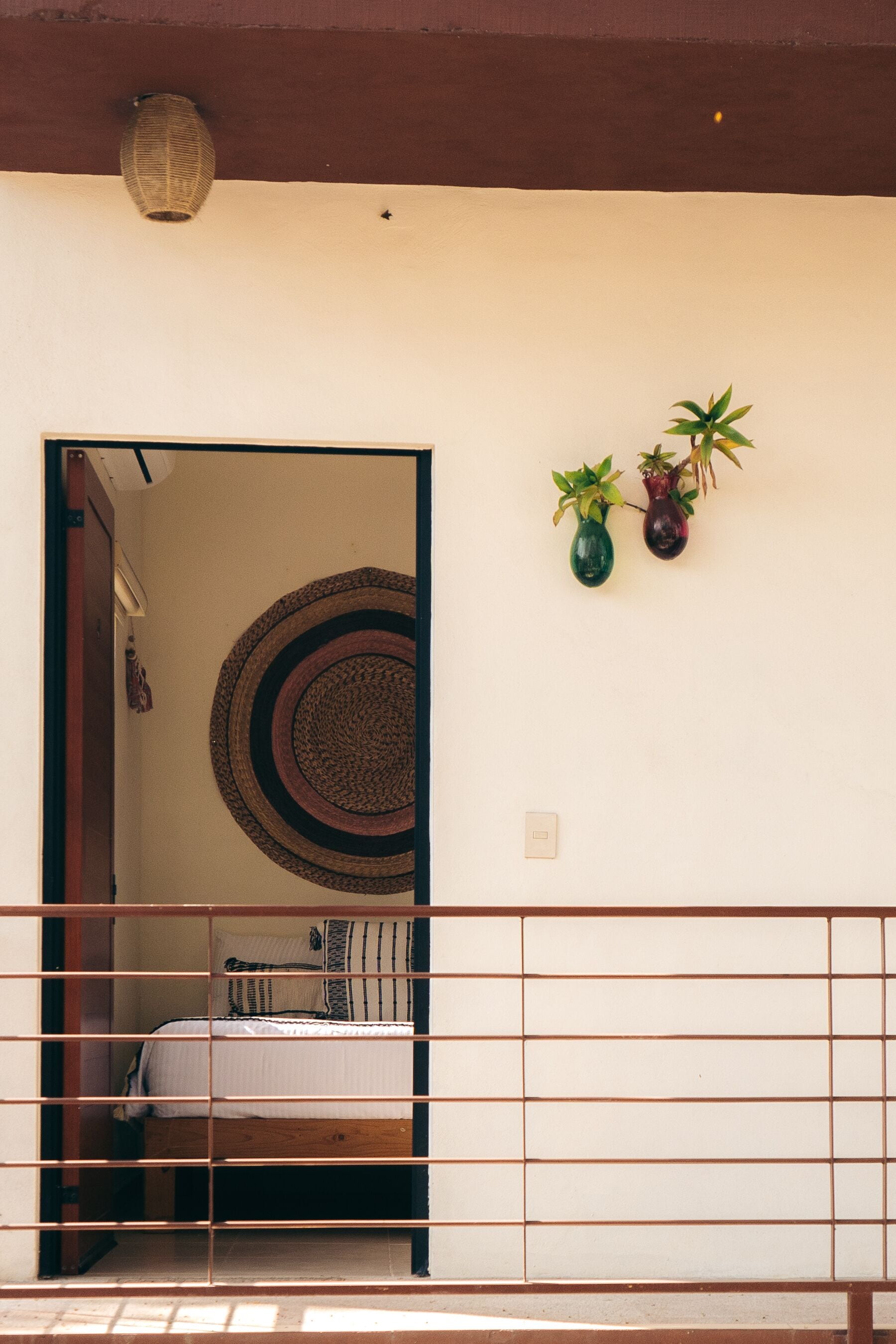 Een kamer met een bed, een wandkleed en twee potplanten.