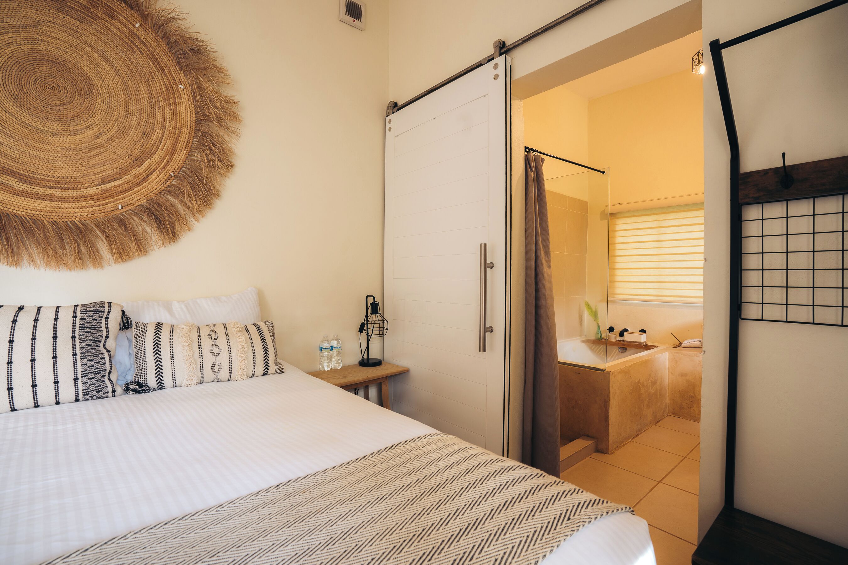Une chambre d’hôtel avec un lit, une table de chevet et une salle de bain visible à travers une porte ouverte.