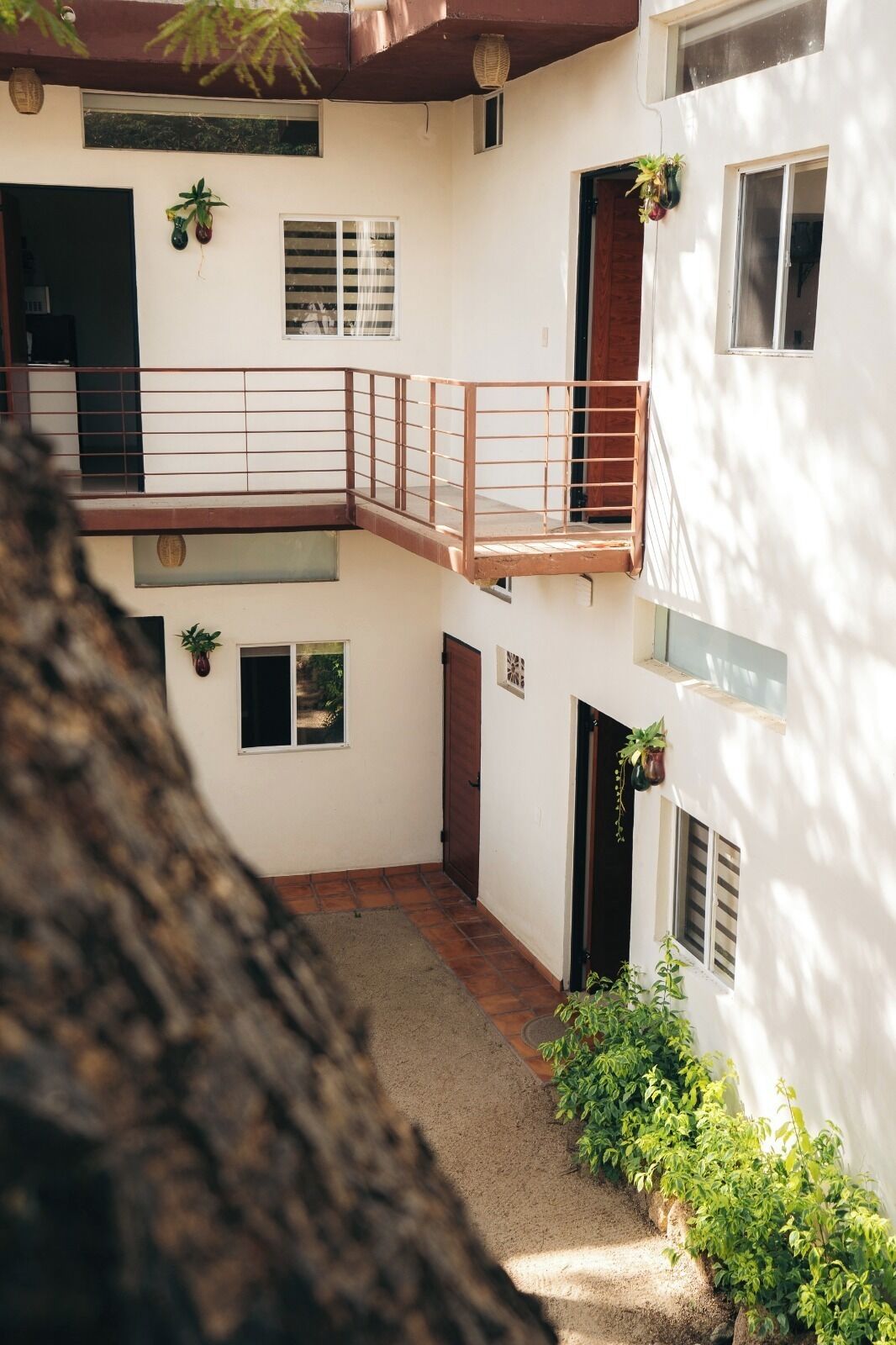 A multi-level building with a balcony, potted plants, and a tiled floor.