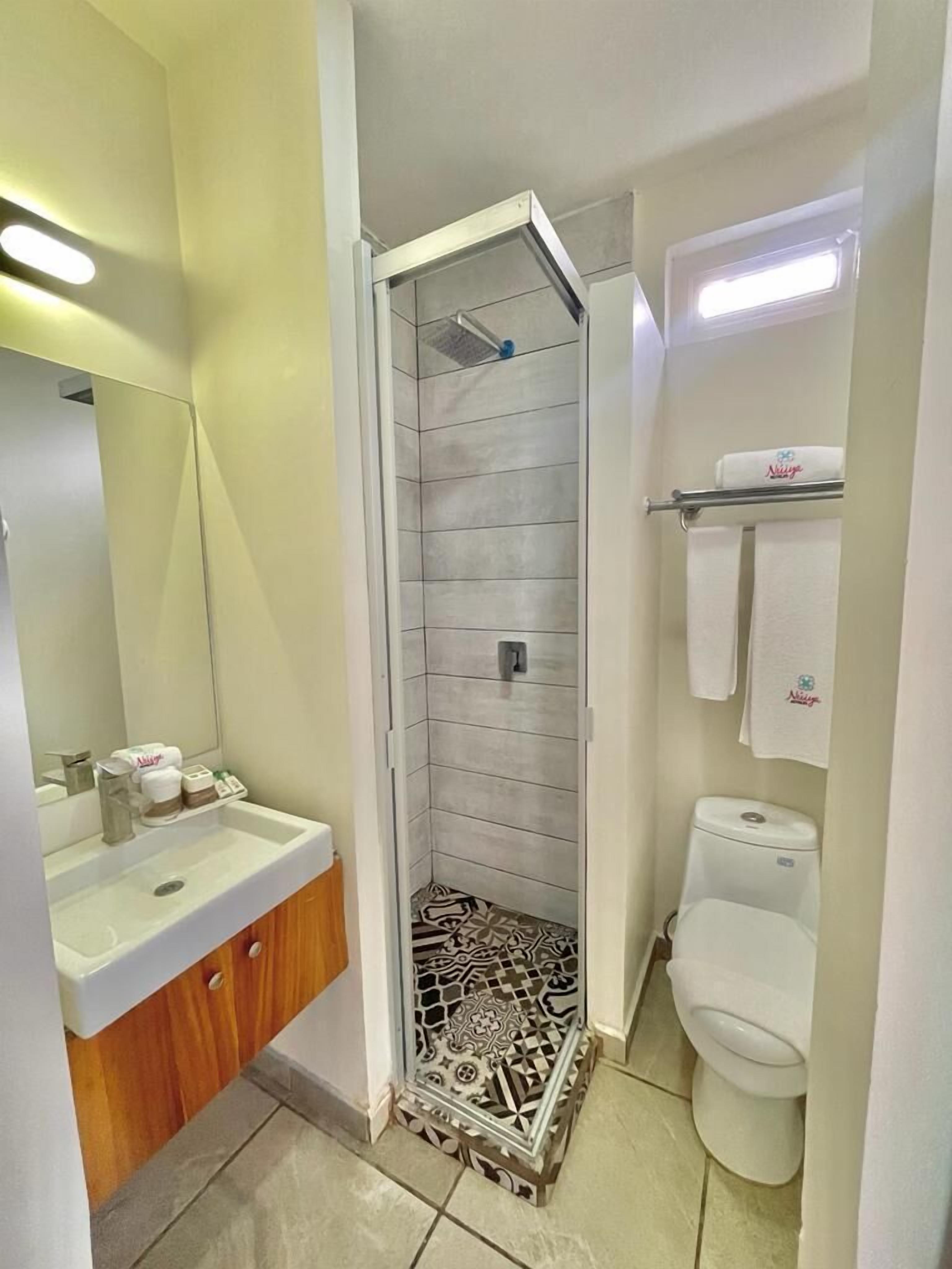 Une salle de bain équipée d’une douche, de toilettes, d’un lavabo et d’un miroir.