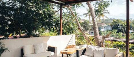 Un área de estar al aire libre con mobiliario de mimbre y una mesa de centro de madera.