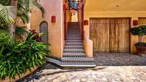 Step into a historic courtyard, surrounded by lush greenery and a beautifully crafted staircase.