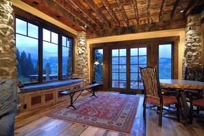 A stone-walled room with large windows, a wooden ceiling, and a view of mountains. - Tipple House (Mt. Crested Butte)