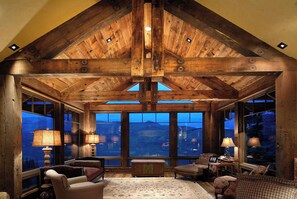 A cozy room with wooden beams, large windows, and a view of the mountains.