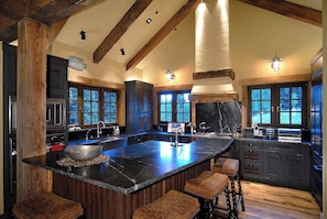 Un'ampia cucina con una grande isola, travi in legno e vista sull'esterno.