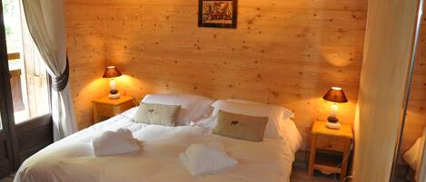 Un dormitorio tipo cabaña de madera con una cama grande, dos mesitas de noche con lámparas y un cuadro enmarcado en la pared.