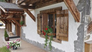 A rustic building with wooden shutters, a wooden porch, and potted plants. - LUXURY CHALET IN MORZINE WITH POOL (Morzine)