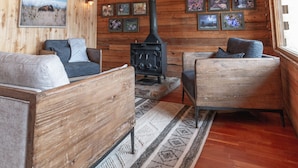 A cozy cabin interior with wooden walls and ceiling, a fireplace, two sofas, and a rug. - Zero Technology and100% Nature (Lake City)