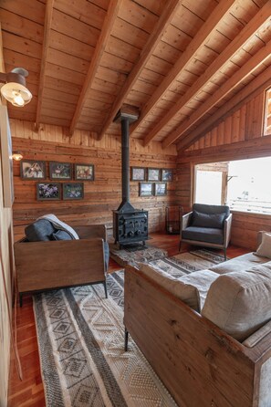 Un acogedor interior de cabaña de troncos con chimenea, paredes de madera y un espacio de estar confortable.