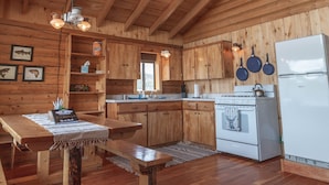 A wooden cabin interior with a kitchen area, wooden beams on the ceiling, and a refrigerator. - Zero Technology and100% Nature (Lake City)