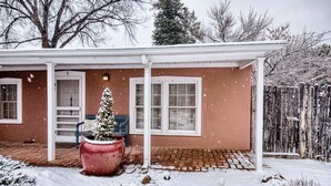 A house with a covered patio, a snow-covered tree, and a brick pathway.