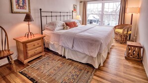 A bedroom with a bed, bedside tables, a chair, a window with curtains, and a rug.