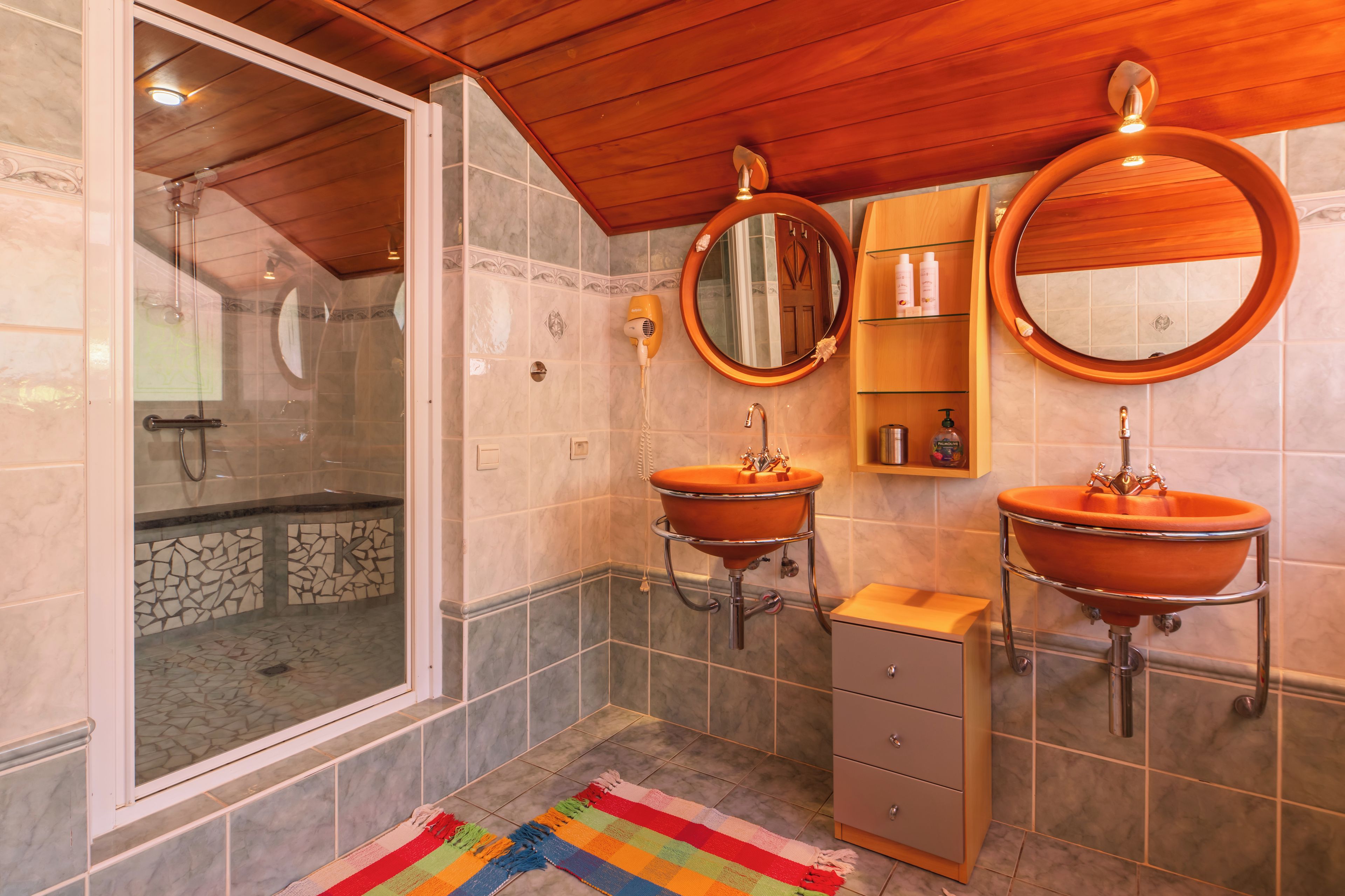 A bathroom with two sinks, a shower, and a vanity with a mirror.