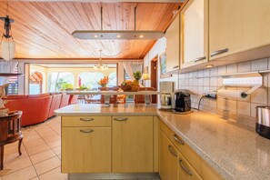 A modern kitchen with wooden cabinets, a granite countertop, and a view of the outdoors.
