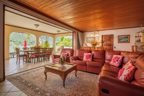 A spacious living area with a wooden ceiling, a dining area with a view, and a cozy seating arrangement.