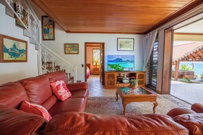 A living room with a leather sofa, a television, and artwork on the walls.