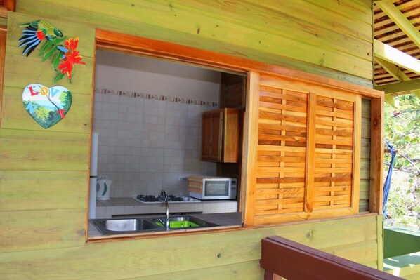 Una cabaña de madera con área de cocina, que incluye un lavabo, estufa y microondas.