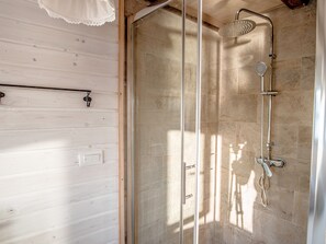 A shower with a glass door, a handheld showerhead, and a handheld shower attachment.