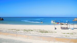 Een strand met helderblauw water, een zandstrand en een redderspost.