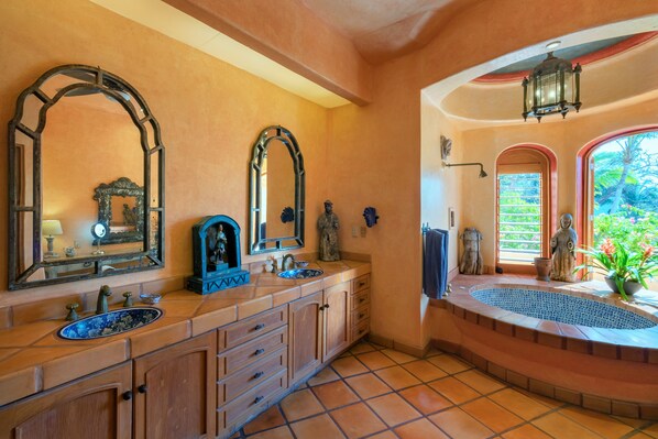 A bathroom with a large vanity, multiple mirrors, a bathtub, and a view of the outdoors.