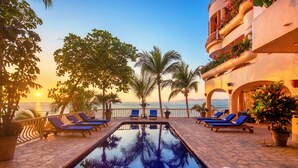 A poolside area with lounge chairs and palm trees, overlooking the sea. - Villa Estrella Mar - 5 Star Luxury Villa - Staff - Private Pool - On the beach! (Puerto Vallarta)